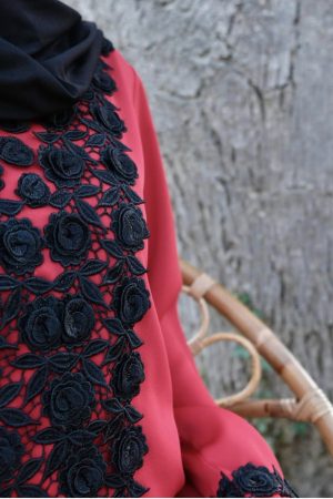 Zoom sur la guipure noire de la robe longue rouge, détail dentelle raffinée sur la poitrine